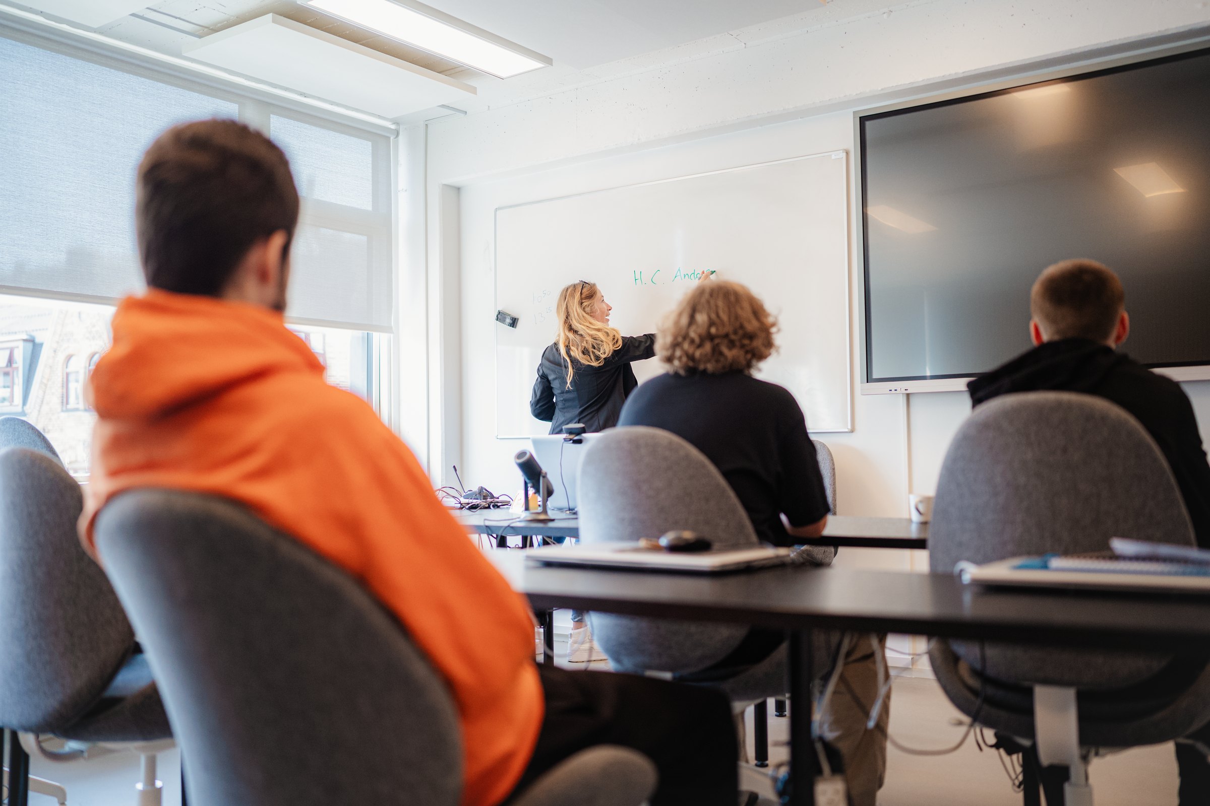 Undervisning i klasselokalet: en underviser skriver på whiteboardet, mens eleverne følger med